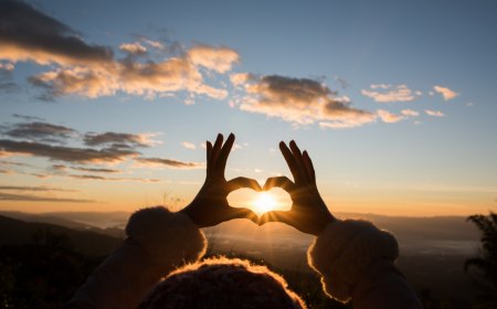 silhouette hands forming a heart shape with sunrise