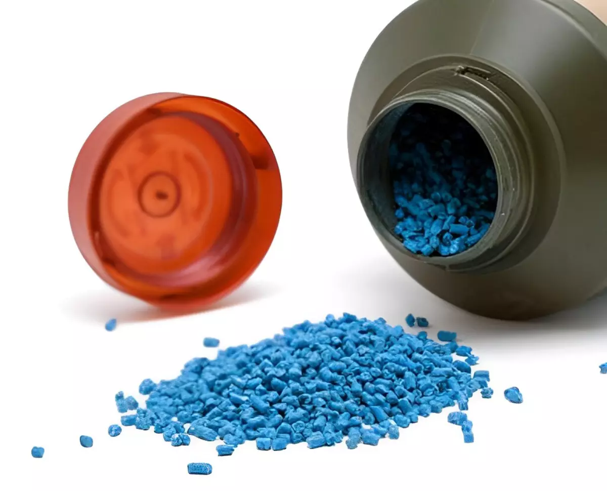granules bleues deversees d une bouteille plastique noires et capuchon rouge