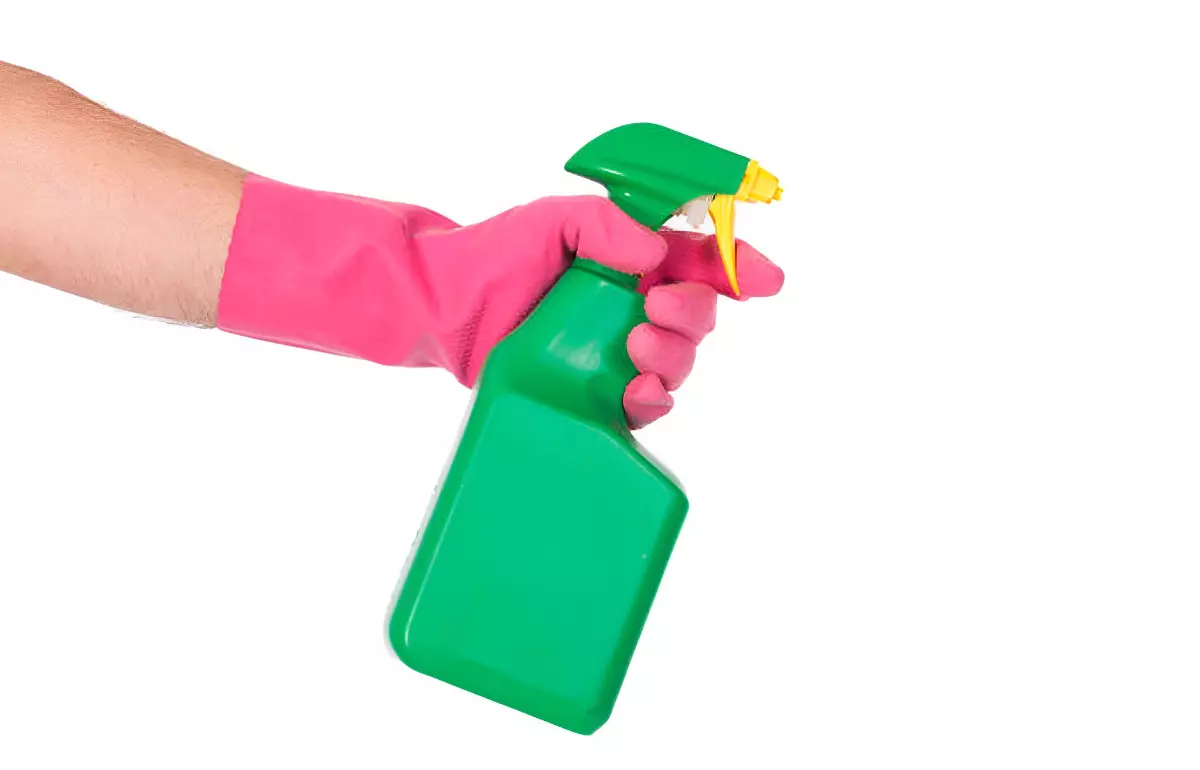 pulverisateur vert tenu par une main gantee en vert sur fond blanc