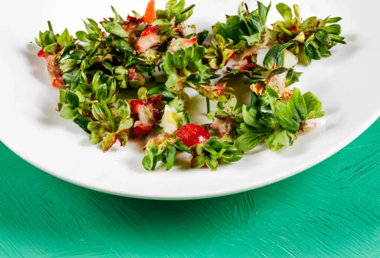 queues de fraises dans une assiette blanche sur une surface verte