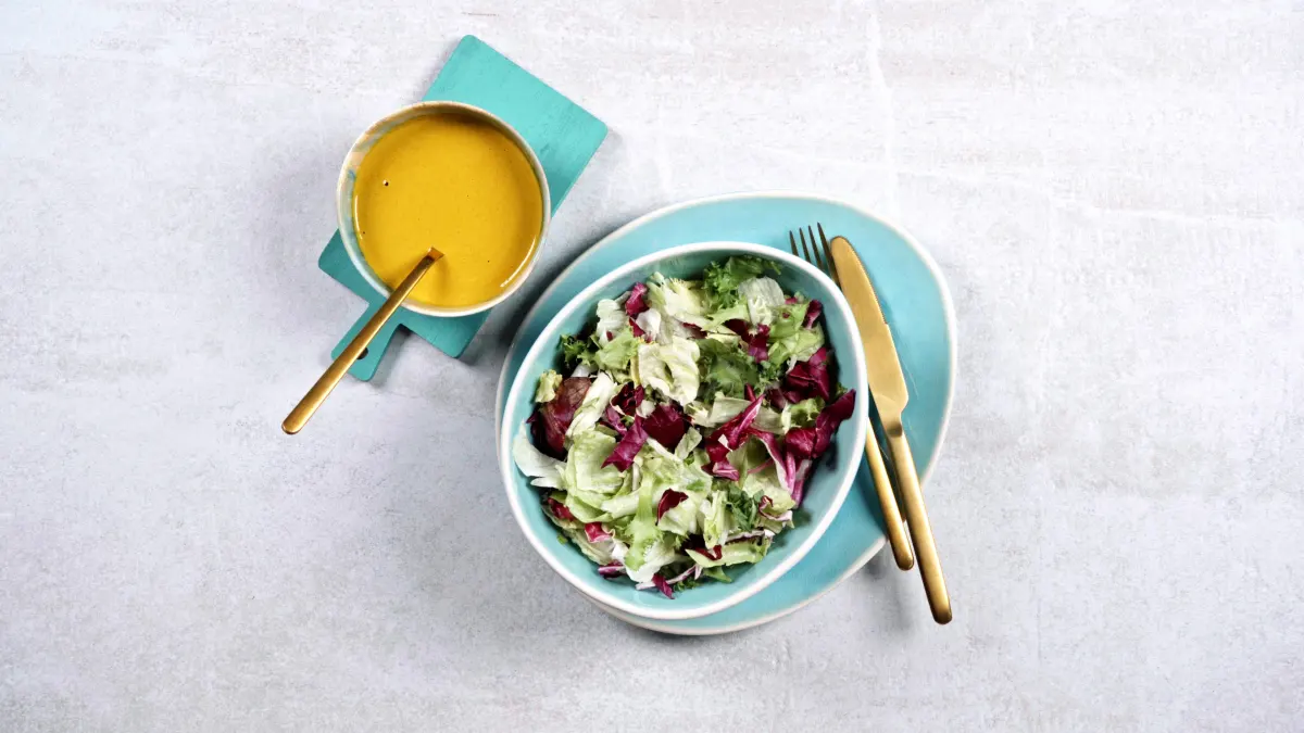 salades melange buddha bowl veggie sauce curcuma assiette bleu planche surface beton