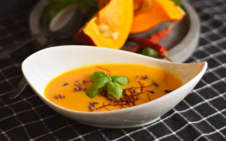 soupe de potiron avec une belle couleur orange dans une assiette blanche sur une nappe en noir et blanc