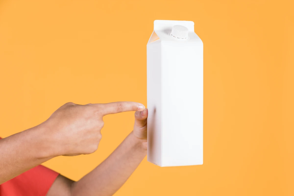 boite de lait sur fond jaune main