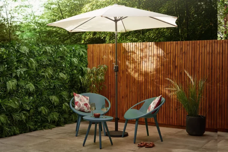 chaise ronde plastique vert fonce table petite ronde parasol beige cloture bois mur vegetal artificiel exterieur