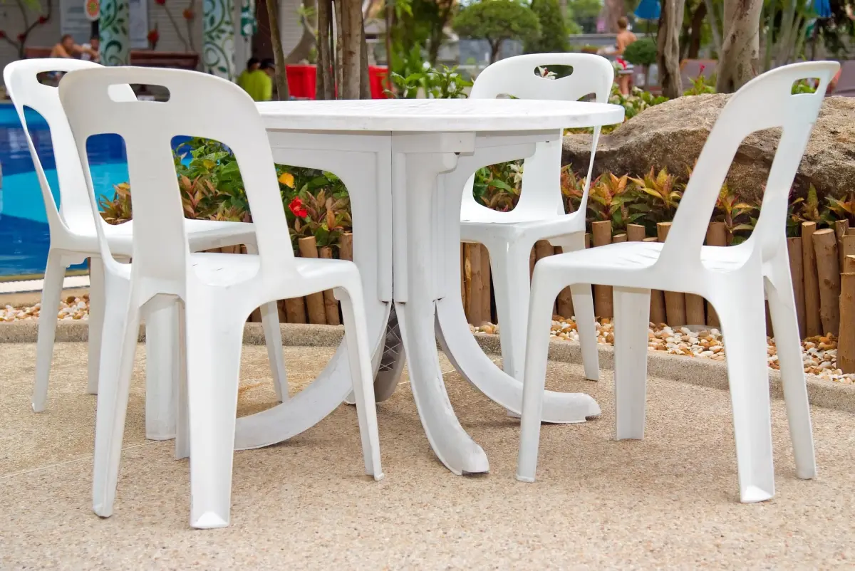 chaises blanches sol beton piscine exterieure table ronde cloture bois