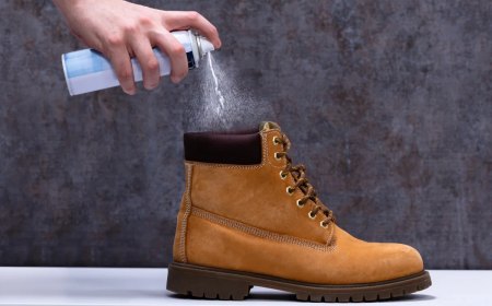 human's hand spraying deodorant on smelly shoes over white desk