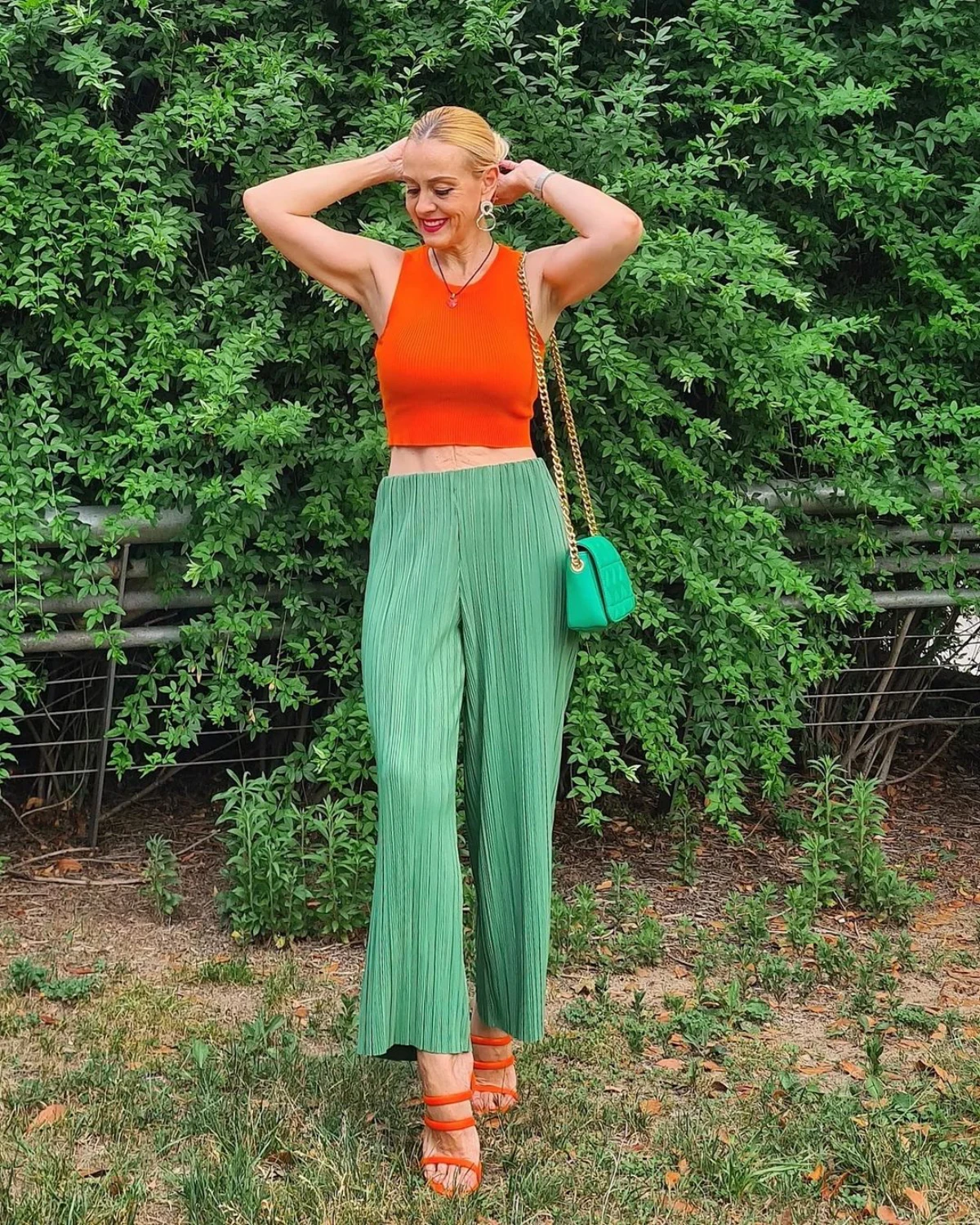 femme 60 ans pantalon vert large haut et chaussure orange jardin
