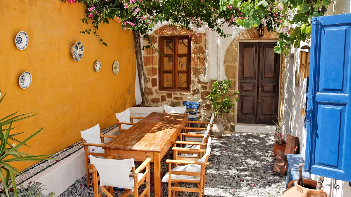 idée salon de jardin exterieur de bois avec mur jaune ocre et revetement sol en pierre plantes mediterraneennes