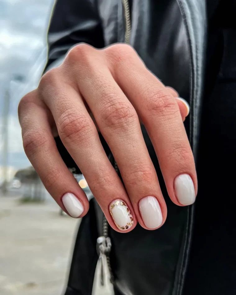 manucure ongles courts vernis blanc laiteux nail art sur un doigt