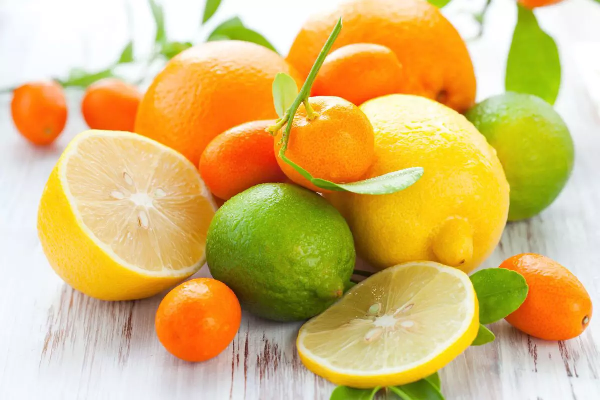 oranges en arriere plan citron jaune entier la moitié d un citron jaune et citron vert au premier plan avec des clementines