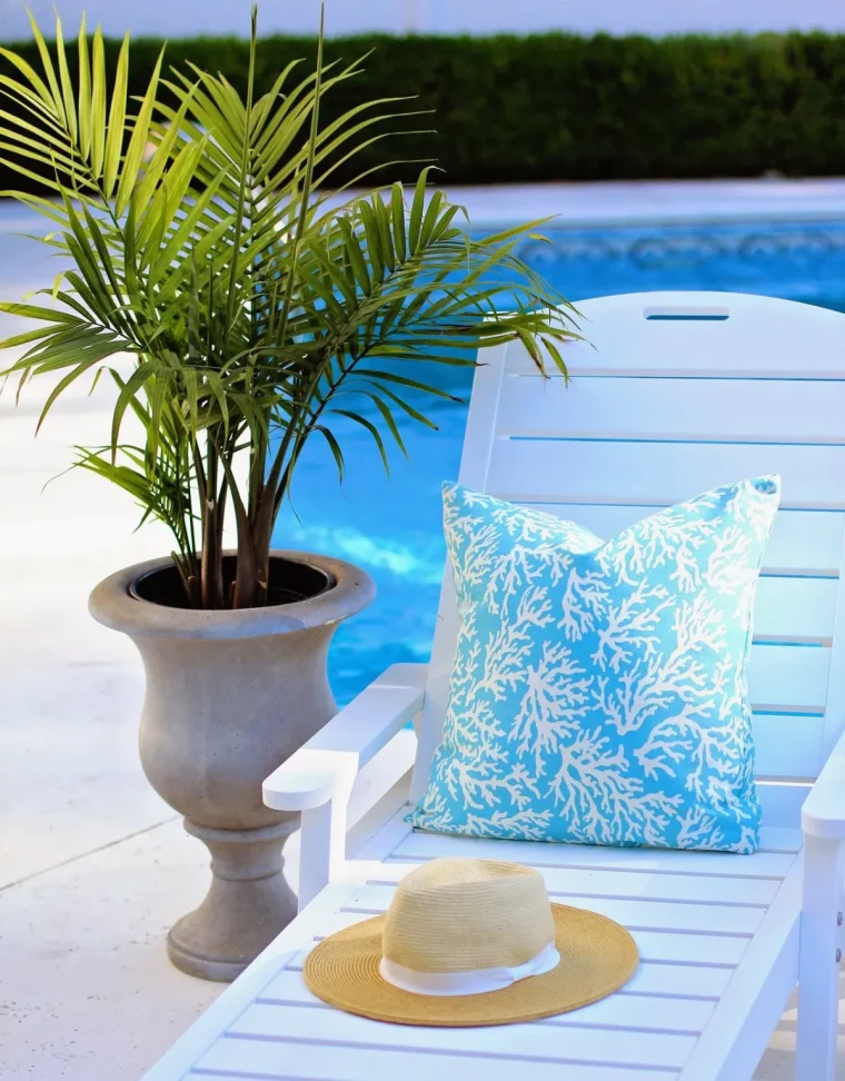 plante verte feuillage palmier en pot transat blanc capeline paille coussin blanc et bleu