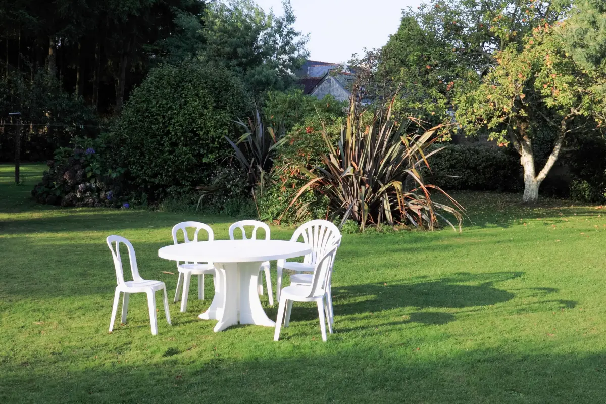 salon de jardin plastique blanc chaises table ronde arbres de jardin plantes ombre lumieres pelouse