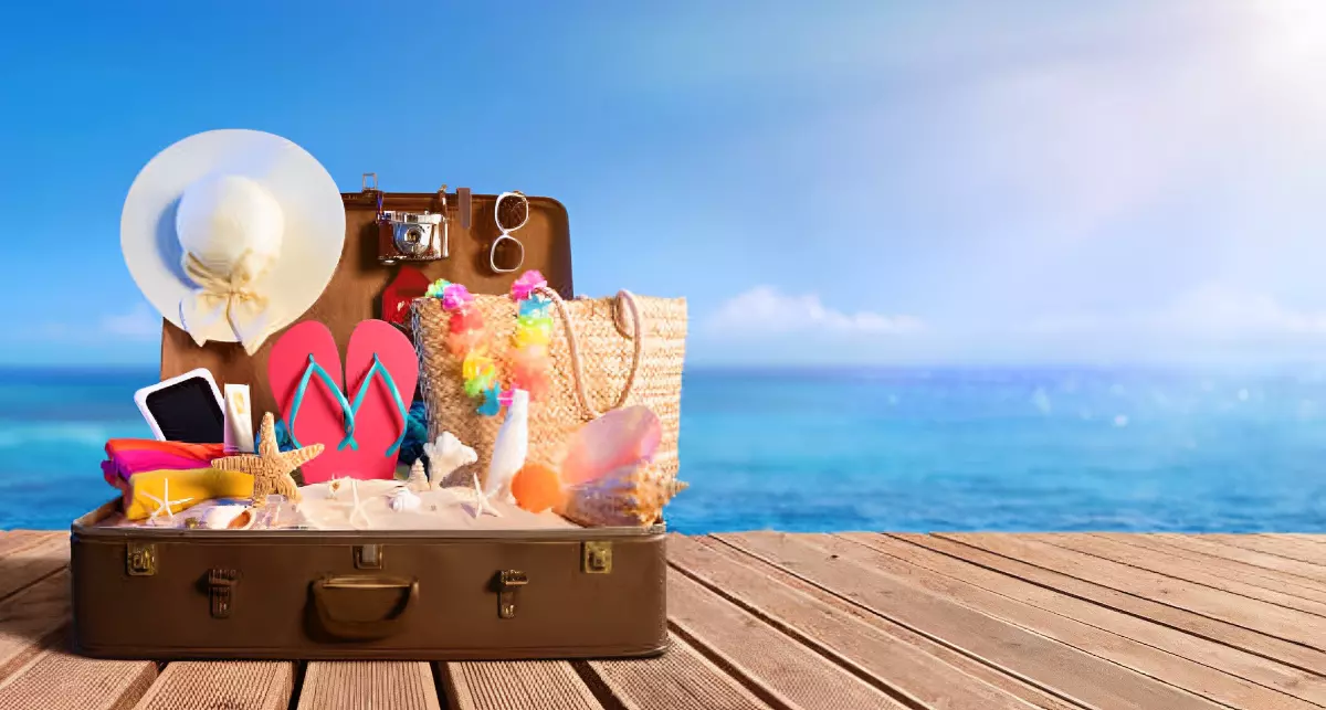 valise ouverte sur un plancher en bois remplie de sable et d affaires pour partir en vacance a la mer sur fond le ciel bleu et la mer