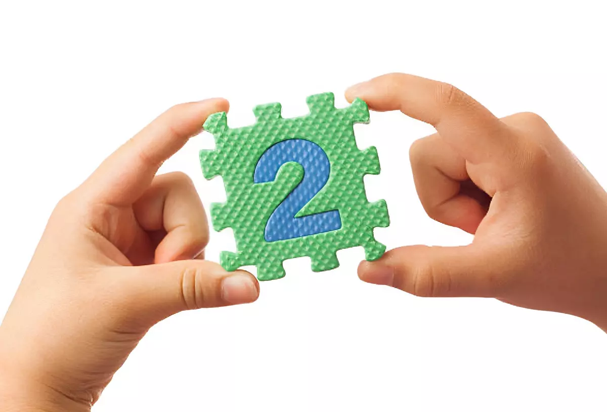 chiffre deux sur une piece de puzzle tenu par deux mains d enfant sur fond blanc