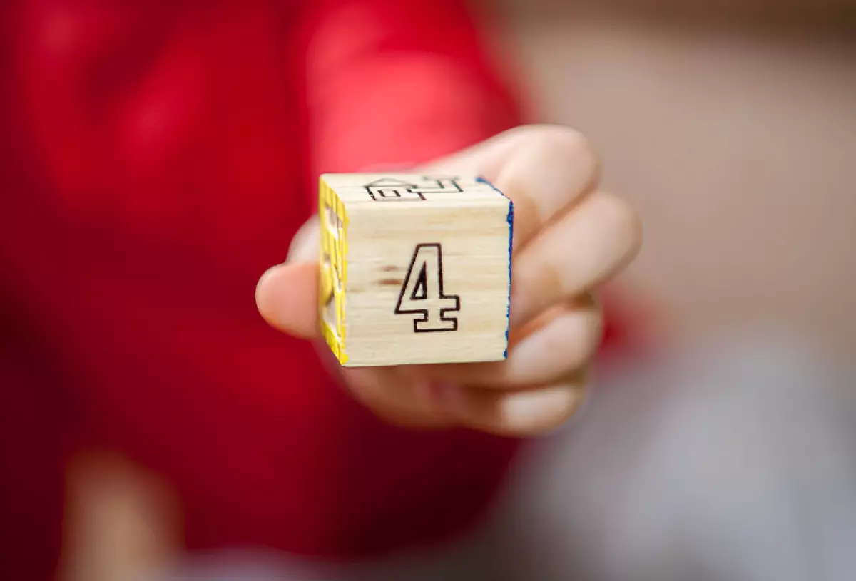 chiffre quatre sur cube en bois tenu par une personne en rouge