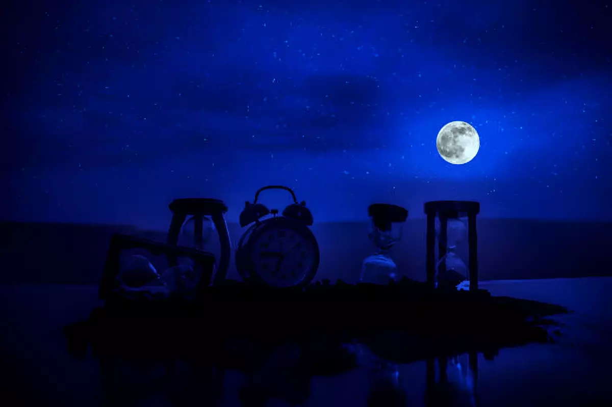 outils pour mesurer le temps au premier plan sous la lumiere du ciel nocturne et la pleine lune