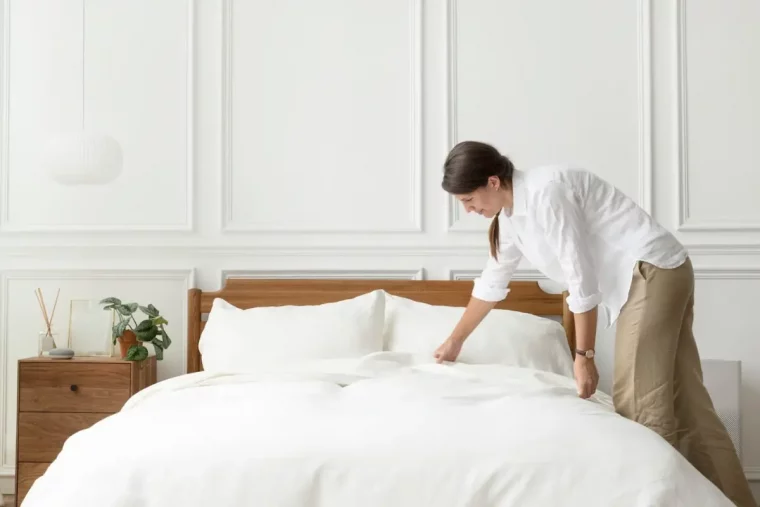 changer draps lit mur blanc lampadaire meuble chevet bois fonce femme