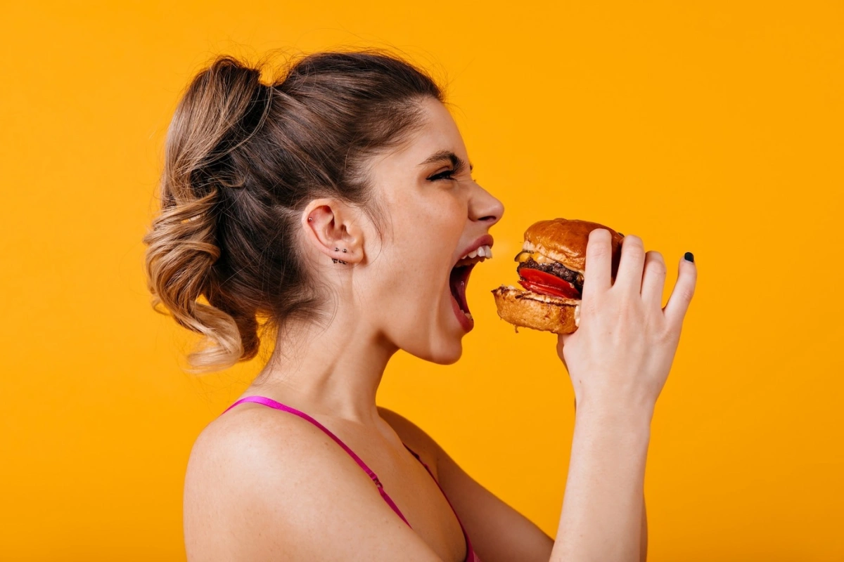 femme balayage blond queue de cheval burger piercing oreille nourriture