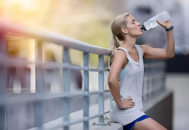 femme blonde en vetements de sport qui bois de l eau d une bouteille plastique