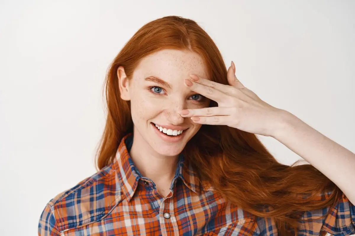 femme cheveux roux longs yeux bleus manucure vernis nude sourire