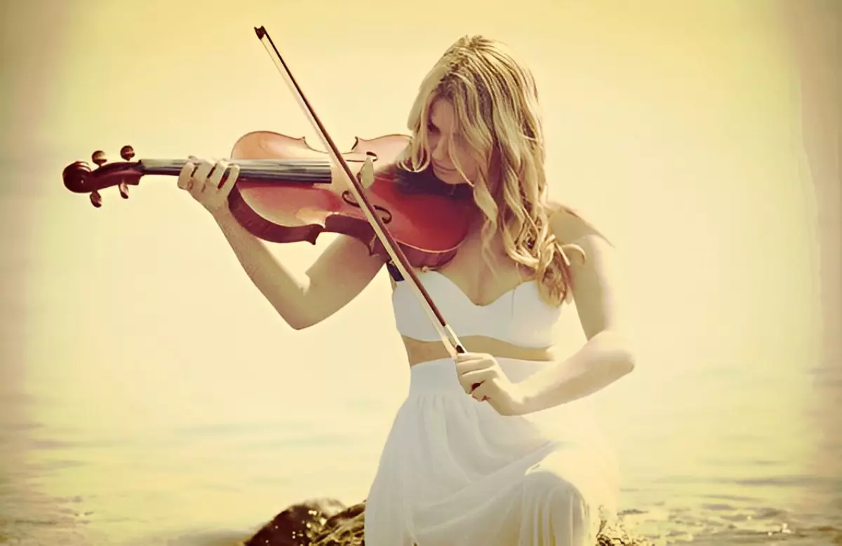 femme habillee en blanc assise au bord de l eau jouant de violon