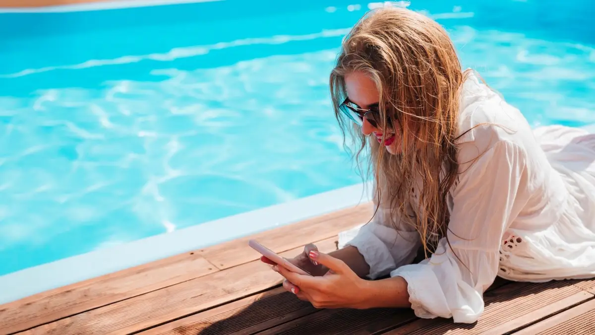 femme telephone terrasse bois piscine eau propre lumiere soleil reflets cheveux mouilles