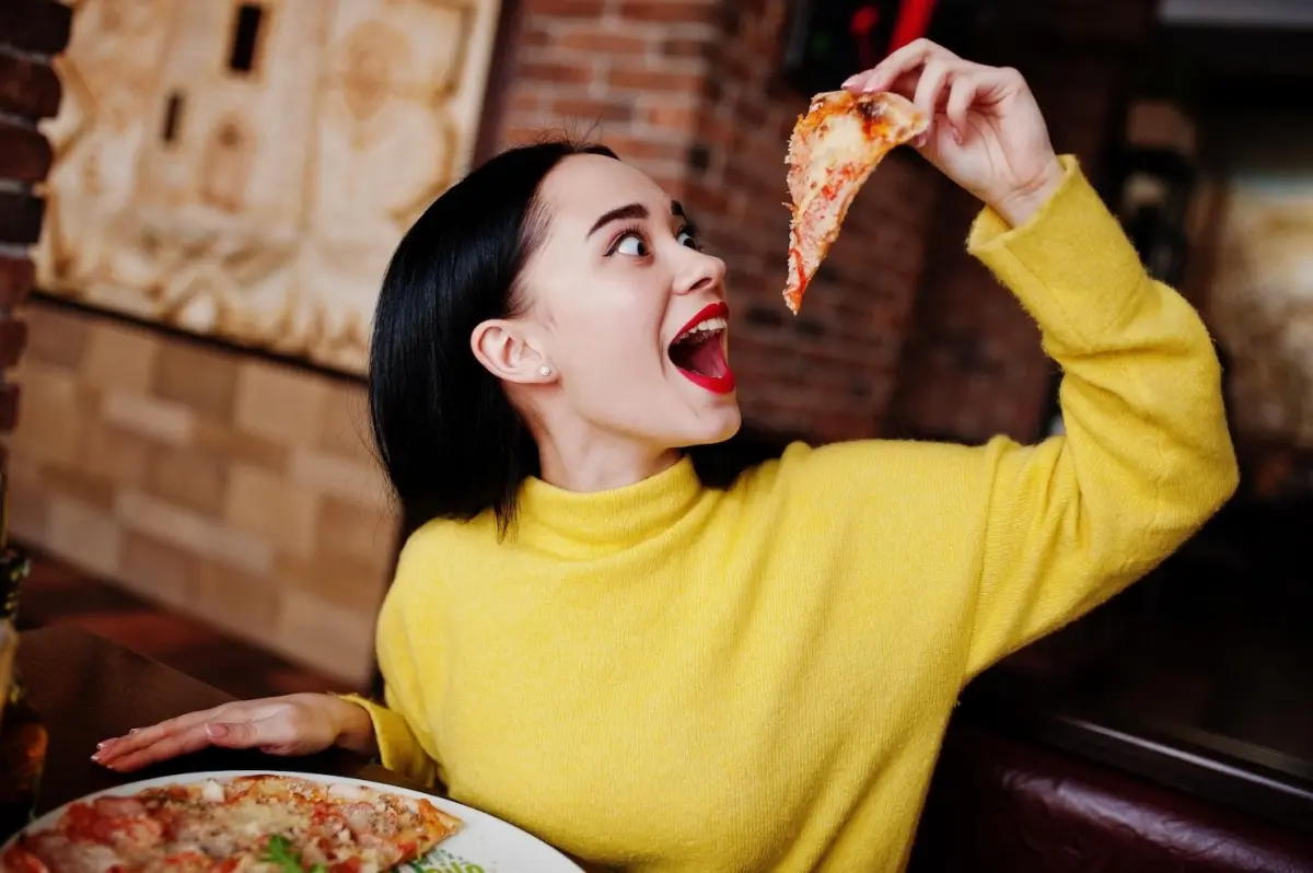 manger pizza tranche assiette ronde femme pull jaune rouge a levre rouge