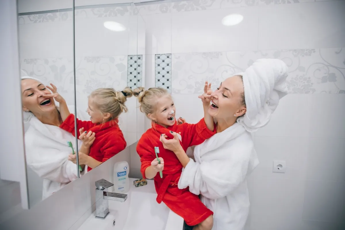 serviettes de bain fille mere brosse dents miroir lavabo carrelage blanc