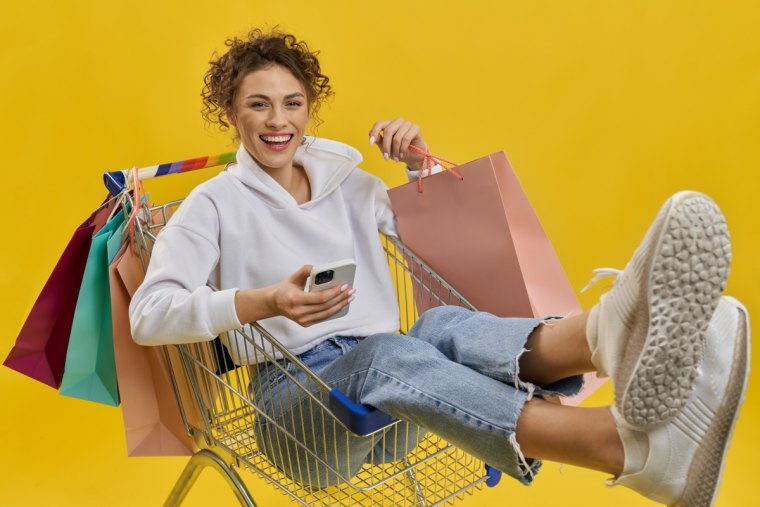 une fille assise avec des achats fond jaune plateforme cashback ebuyclub