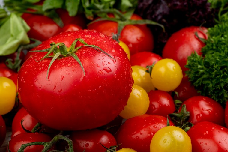 side view of vegetables as spinach coriander and tomatoes as background