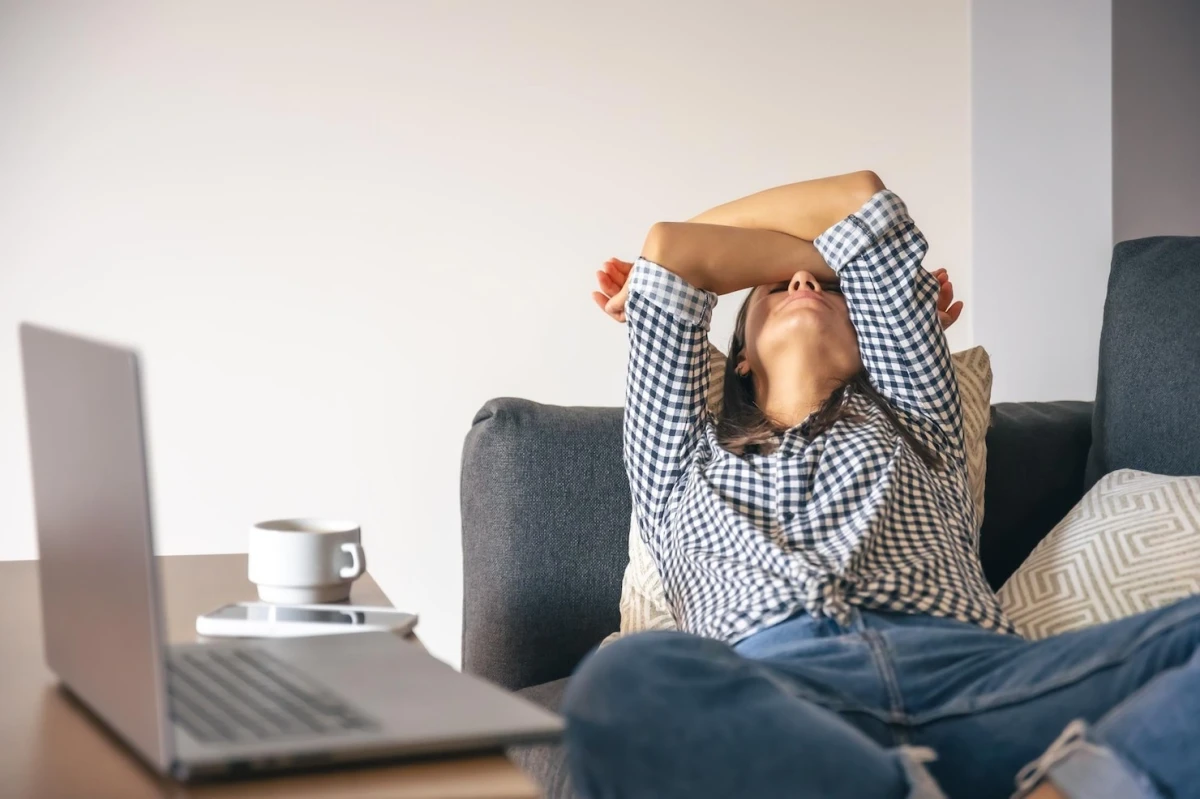 fatigue epuisement femme canape chemise carreaux jeans tasse cafe ordinateur