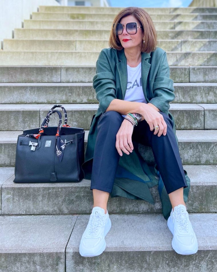 femme 50 ans tendance baskets blanche sac noir veste verte escalier