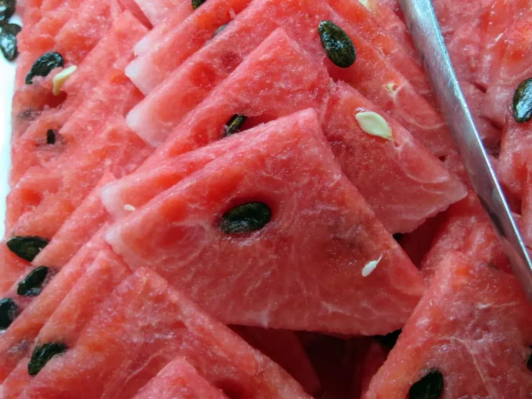 gros plan sur des morceaux decoupes de pasteque rouge avec ses graines noires