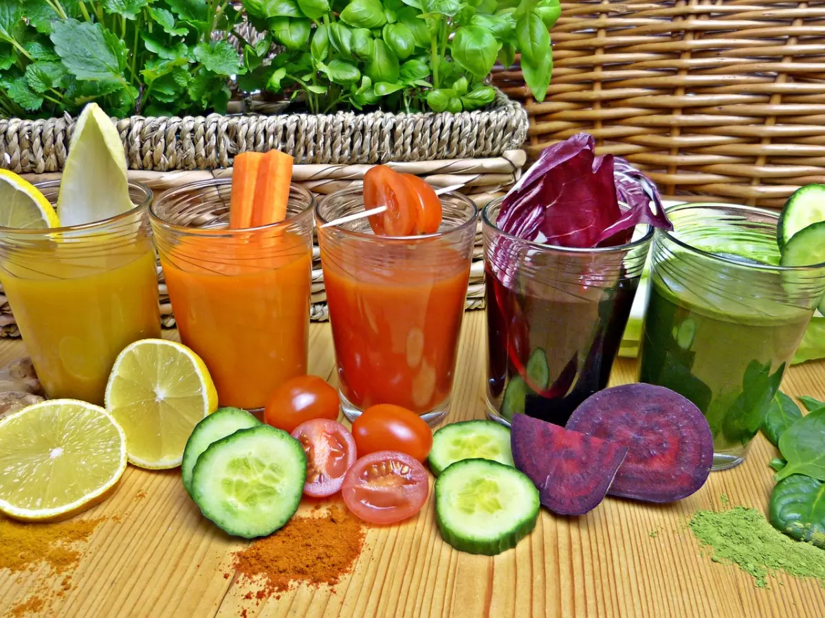 smoothie de differentes couleurs de fruits et legumes poses devant les recipients pleins