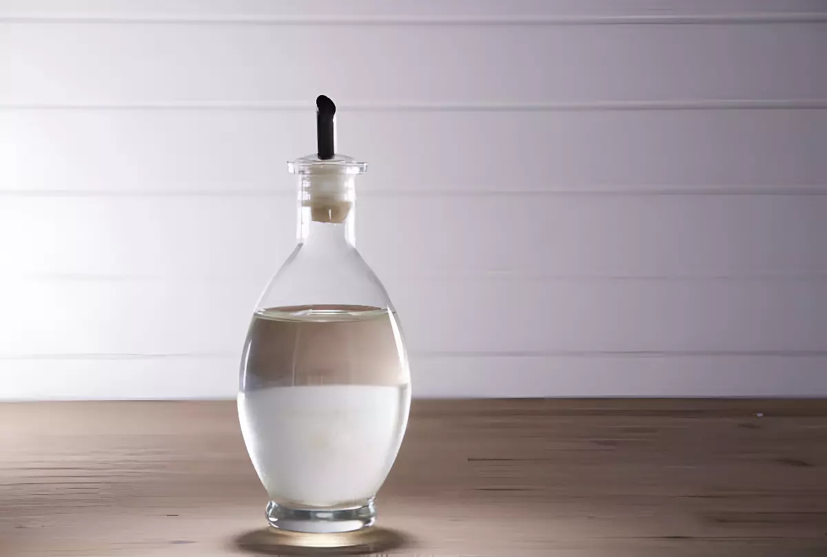 vinaigre blanc dans une bouteille en verre transparent sur une surface en bois et fond blanc