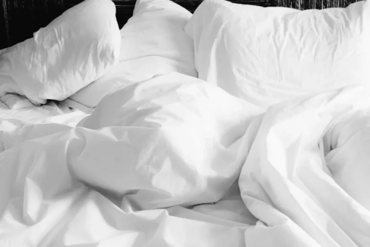 zoom sur un lit defait avec des draps blancs