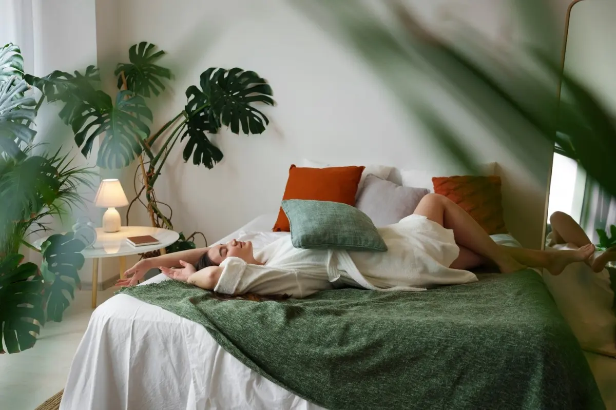 decoration chambre a coucher avec plantes vertes monstera deliciosa femme lit couverture vert fonce