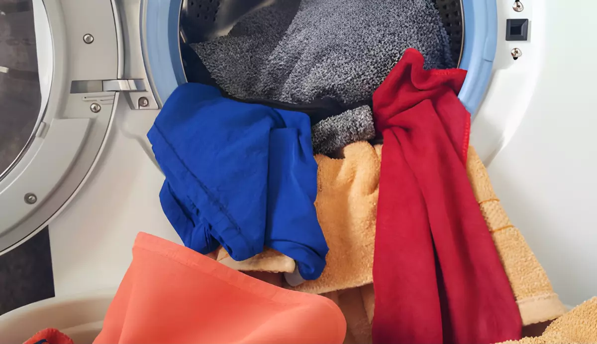des serviettes de differentes couleurs qui debordent du lave linge