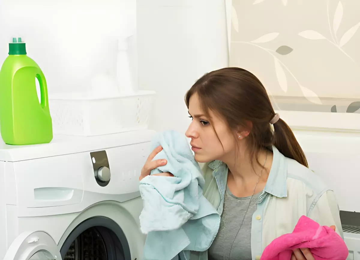 femme devant une machine a laver renifle une serviette