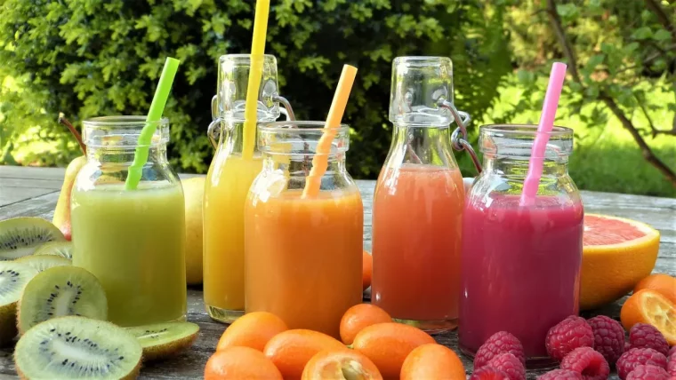 jus de fruits de differentes couleurs avec des pailles avec de fruits frais autour