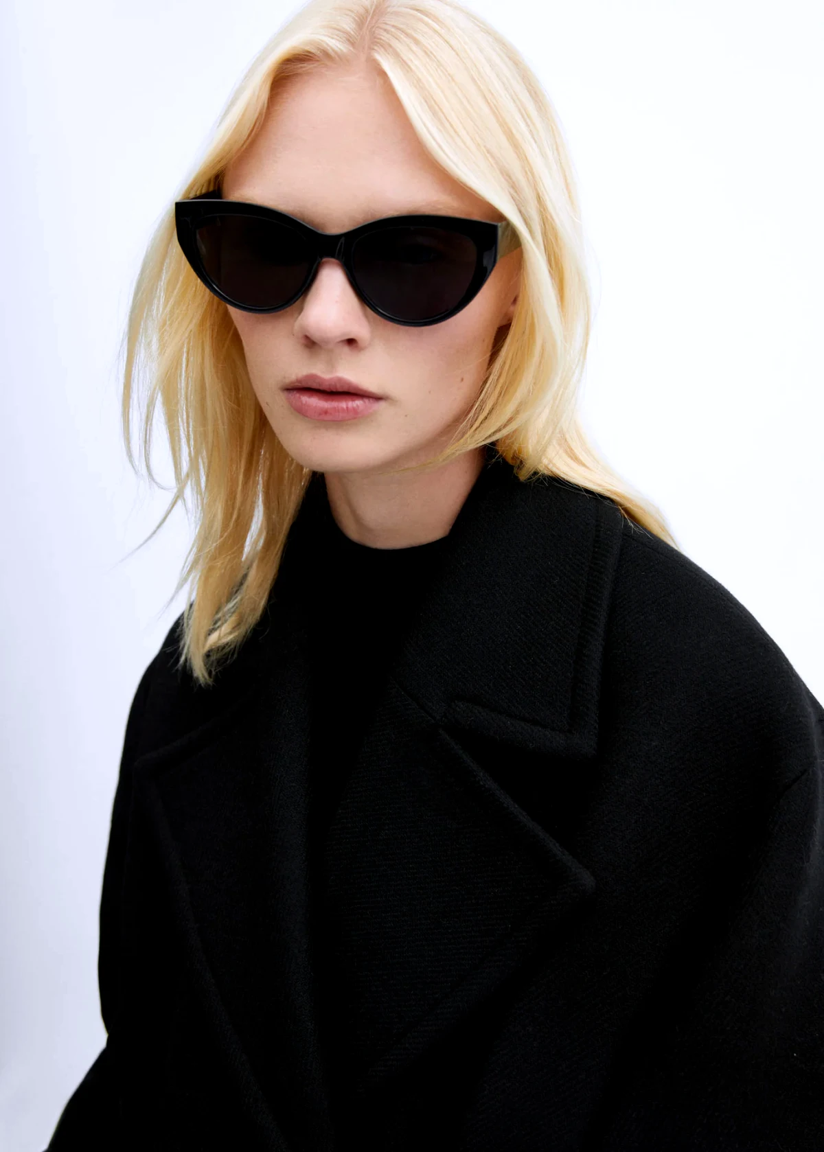 manteau long en laine noir femme blonde lunettes noires
