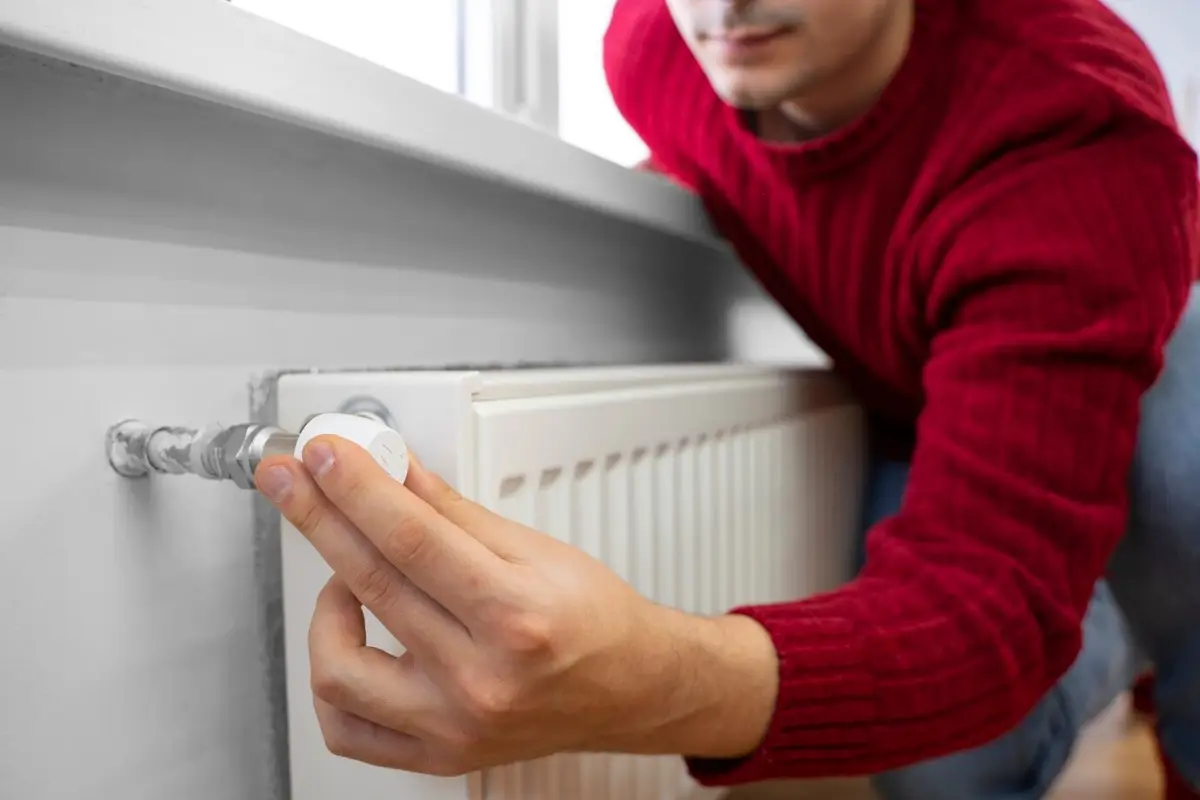 reglage temperature chauffage mur blanc homme pull rouge radiateur