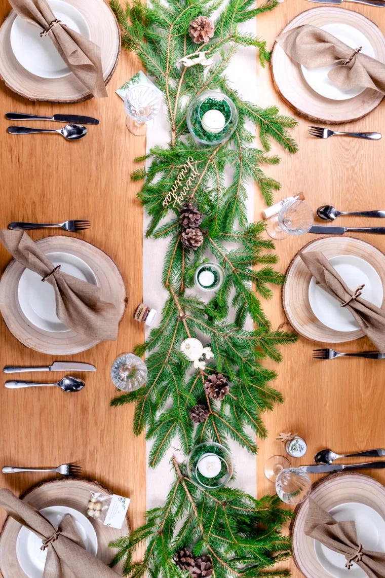 centre de table avec des branches de sapin vertes assiettes blanches