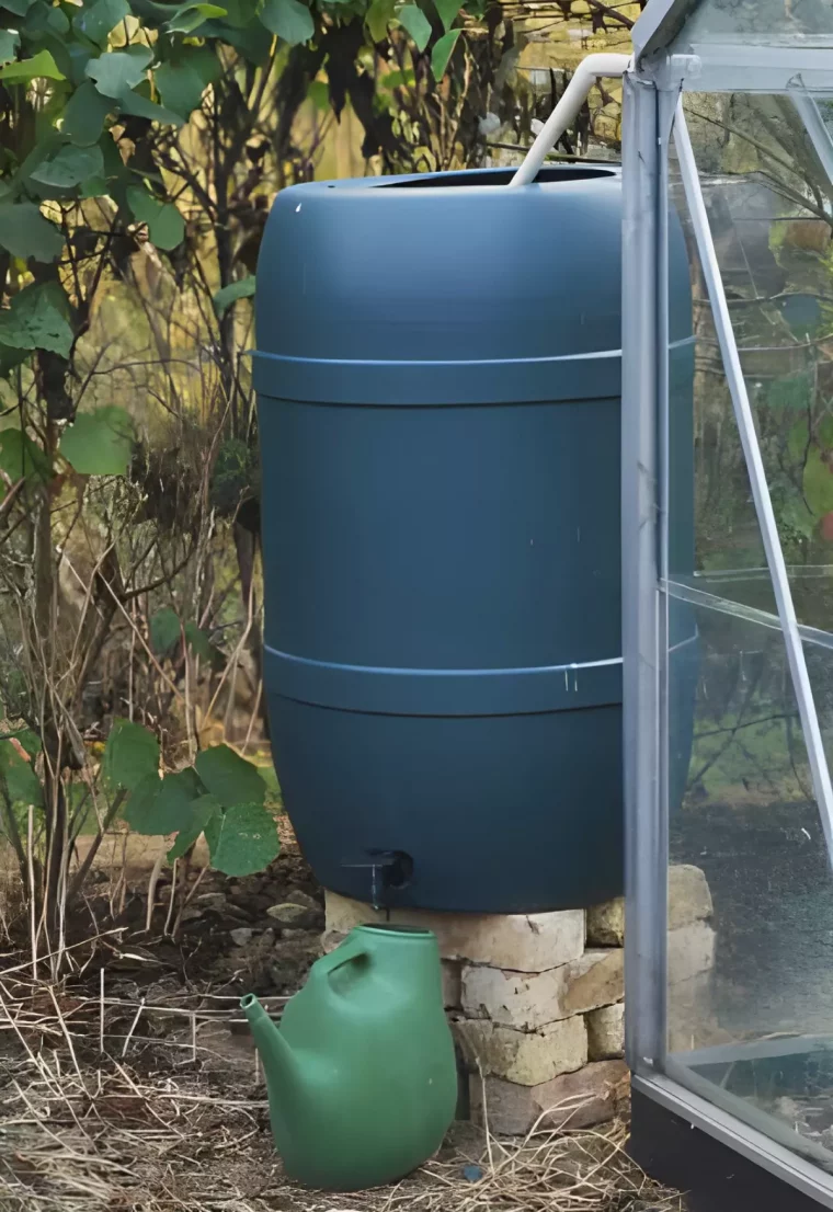 cuve bleue surelevee sur des briques et ouverte au dessus avec un arrosoir vert devant