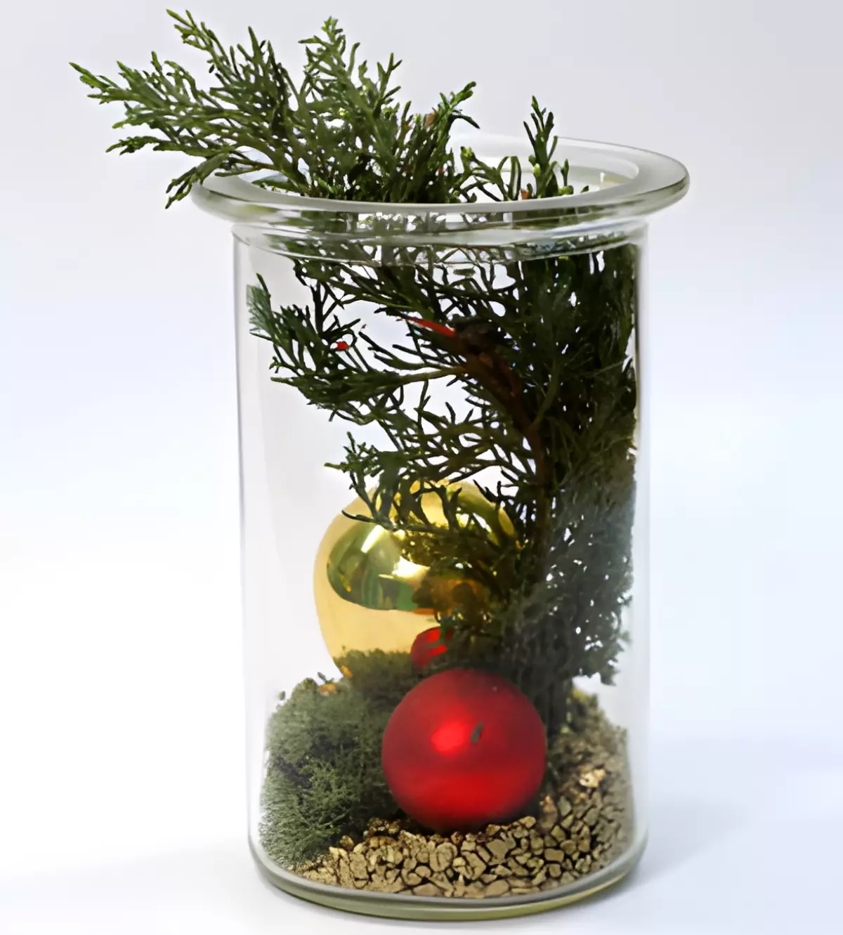 decoration composee d un recipient en verre transparent avec une branche de sapin deux boules couleur or et rouge sur fond de cailloux couleur or