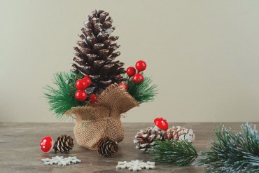 pinecone decorated with holly berries and branches on marble table