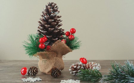 pinecone decorated with holly berries and branches on marble table