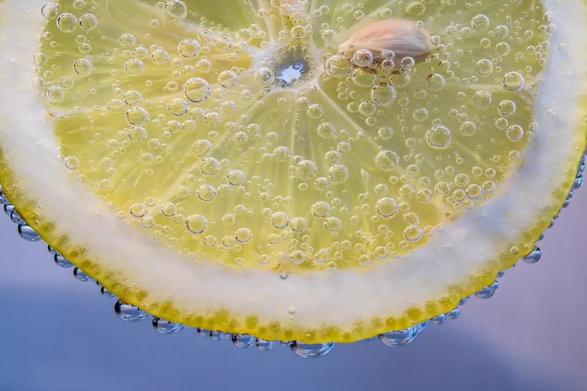 gros plan d une tranche de citron avec des bulles d air sur toute sa surface sur fond bleu