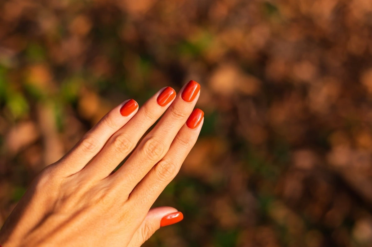 ongles vernis rouge feuilles automne soleil mains femme manucure en gel