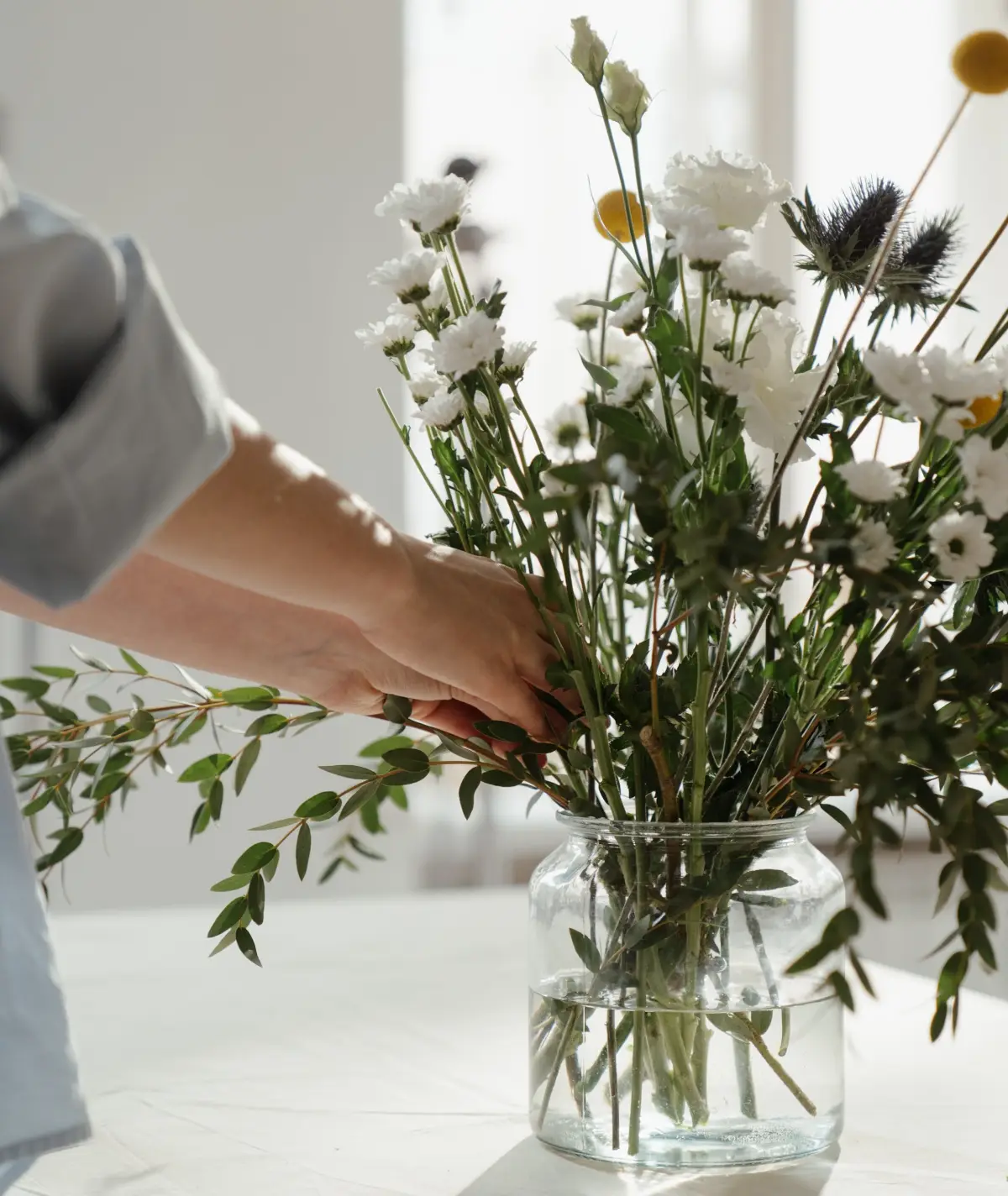 vase bouquet fleurs variete chrysanteme blanc main femme fenetre soleil